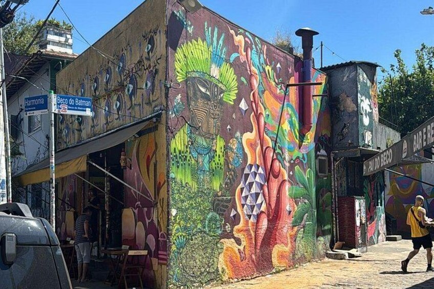 Une fresque colorée sur un bâtiment, un panneau de signalisation et une personne qui marche. 4