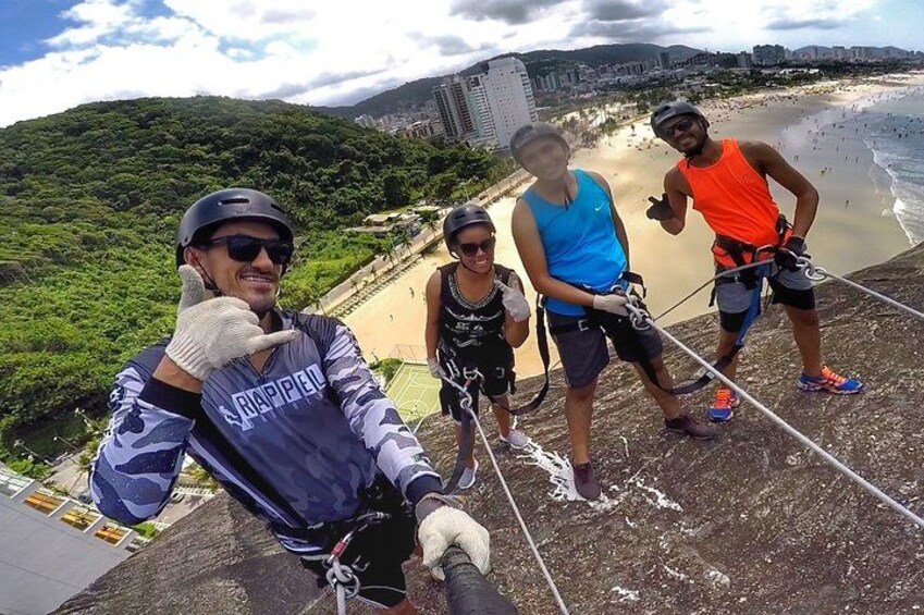 A group of people engaged in a rappelling activity with a coastal cityscape in the background. 2