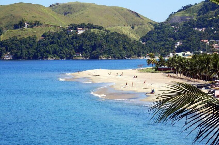 A beach with people, palm trees, and hills in the background. 3