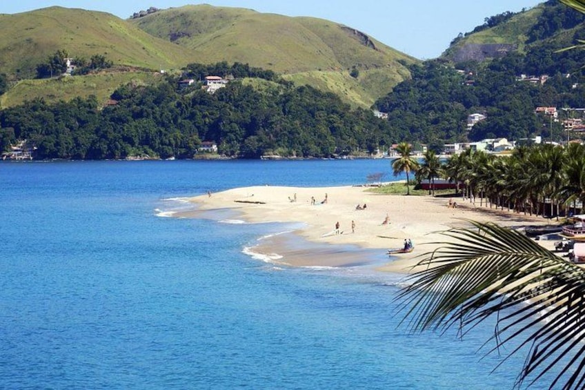 A beach with people, palm trees, and hills in the background. 2