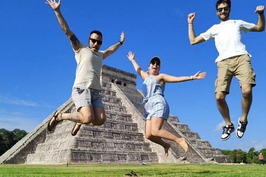 Three people jumping in front of a pyramid. 1