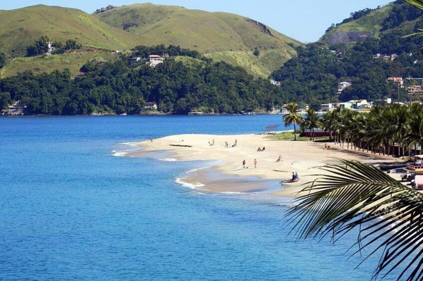 A beach with people, palm trees, and hills in the background. 2