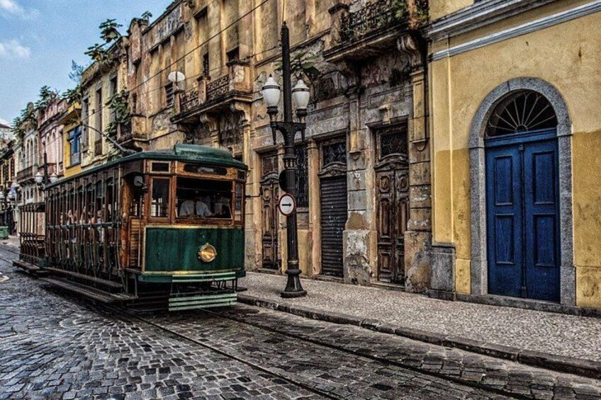A green tram on a cobblestone street, historic buildings, and a blue door. 3