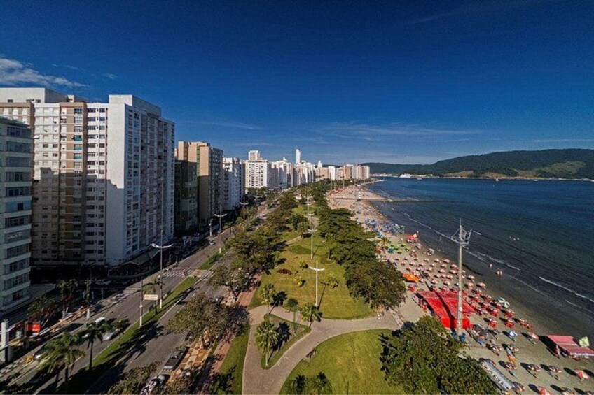A coastal cityscape with high-rise buildings, a beach with umbrellas, and a clear blue sky. 2