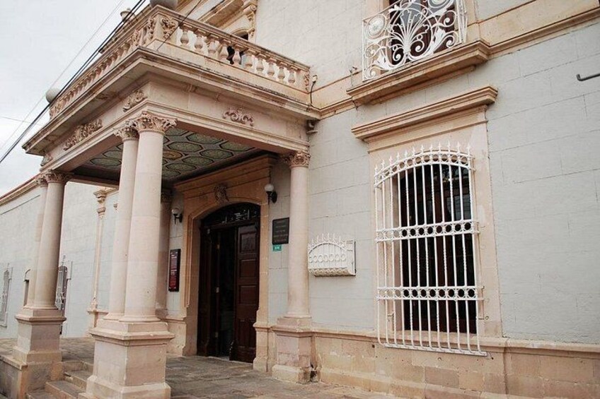 A classical building with a grand entrance, columns, and a decorative balcony. 3