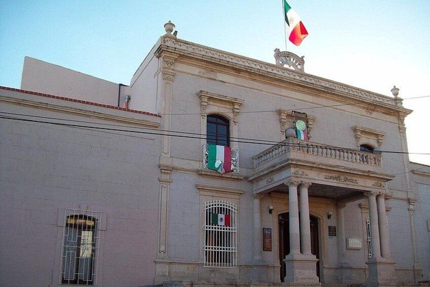 A historic building with a balcony, columns, and a flag. 2