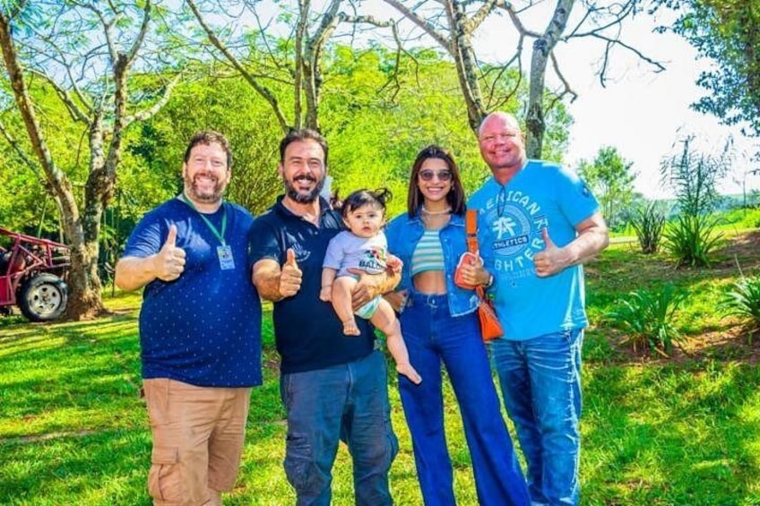 A group of people standing outdoors with trees and grass in the background. 4