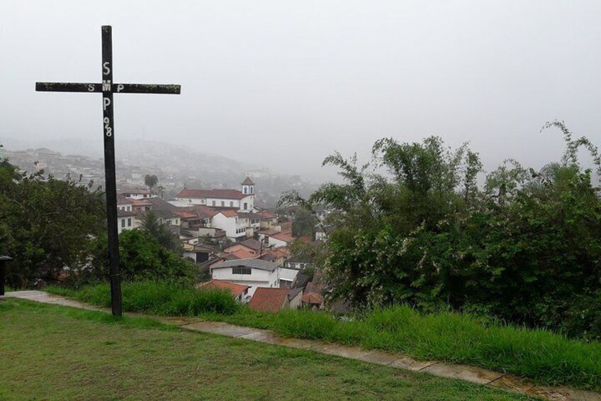 A crossroad sign with 'S' and 'P' directions, a church, and a residential area in the background. 5