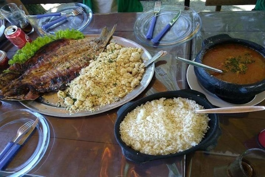 A meal with grilled fish, rice, and a stew on a table. 3