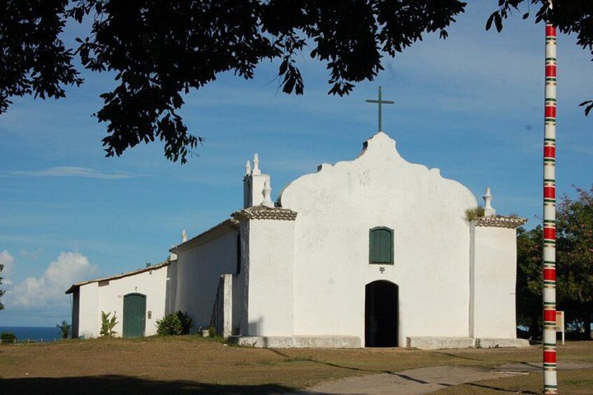 A white church with a cross on top, a red and white pole, and a clear blue sky. 3