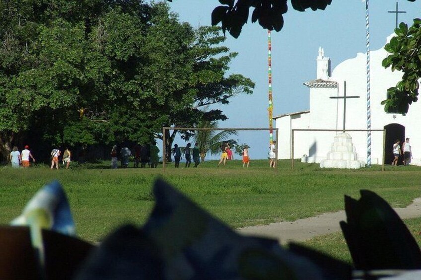 A white church with a cross, a group of people, and a grassy field. 4