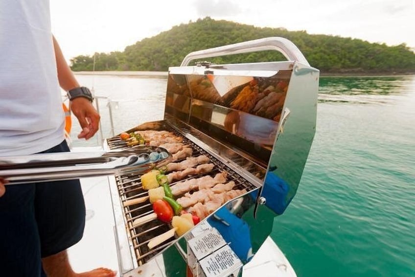 Une personne qui fait griller différents types de viande et de légumes sur un barbecue portable à bord d’un bateau. 5