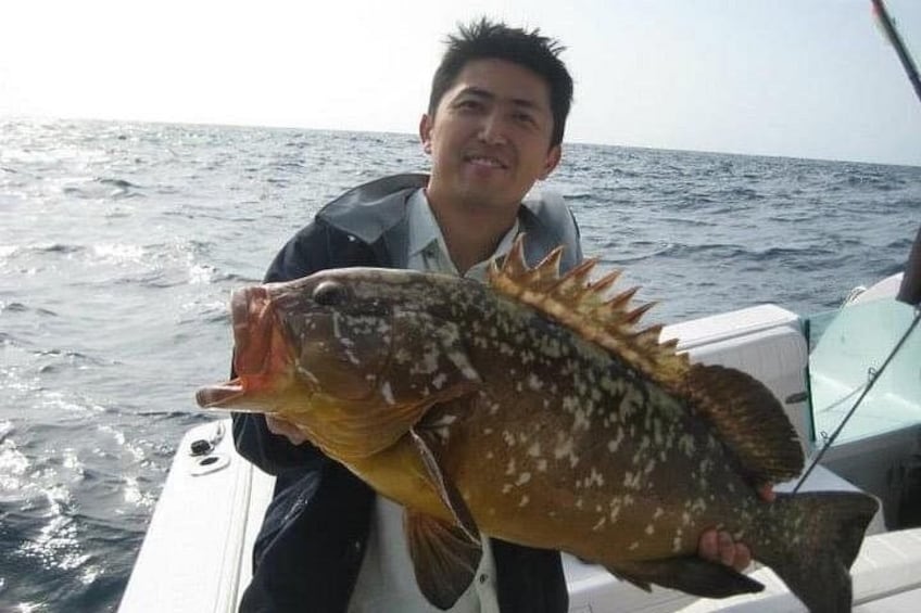 A person holding a large fish on a boat in the ocean. 1