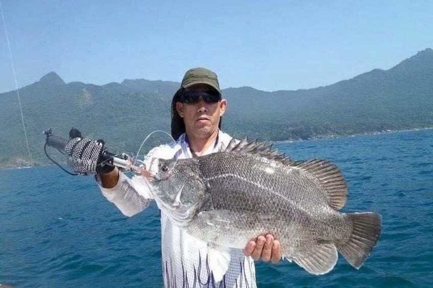A person holding a large fish with a fishing rod. 3