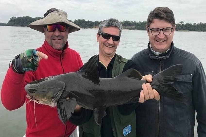 Three people holding a large fish. 5