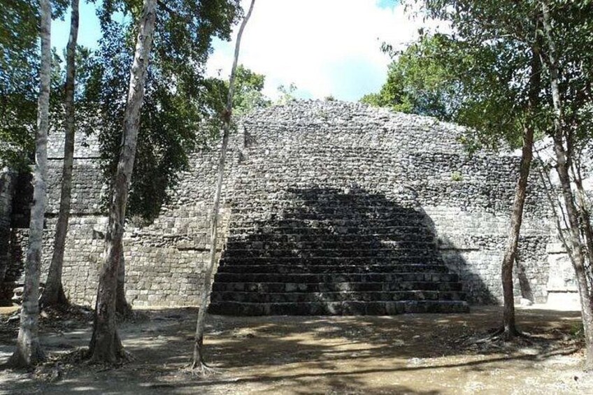 A stone pyramid structure surrounded by trees. 2