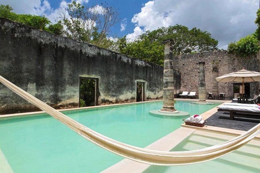 Ein Pool mit Hängematte, Liegestühlen und einer Steinmauer. 1