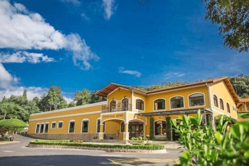 A yellow building with a red roof, surrounded by greenery and trees. 2