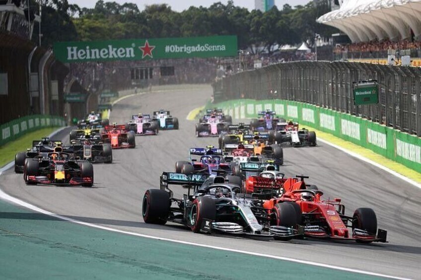 A Formula 1 race on a track with multiple cars, a Heineken advertisement, and a hashtag #ObrigadoSaenna. 1