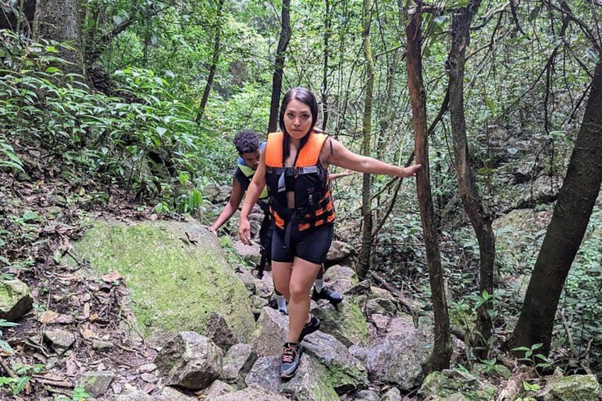 Una persona caminando por un área boscosa con rocas y árboles. 2