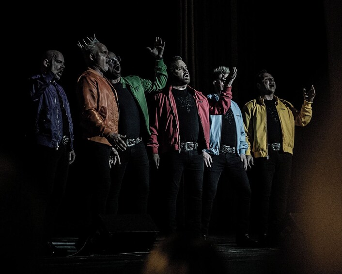 A group of people on a stage with a dark background. 2