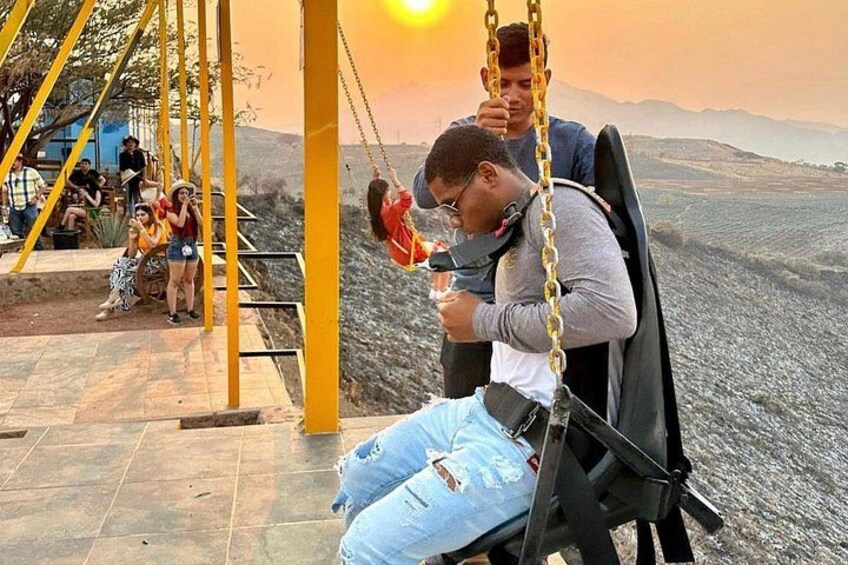 A person on a swing with a sunset in the background. 4