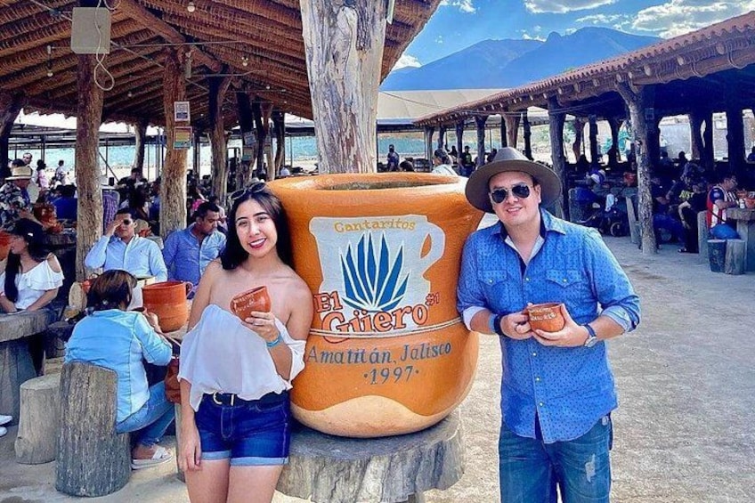 A large beer keg with a label, people sitting at tables, and a mountainous landscape in the background. 3
