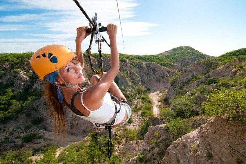A person bungee jumping with a helmet and harness, surrounded by a mountainous landscape. 1