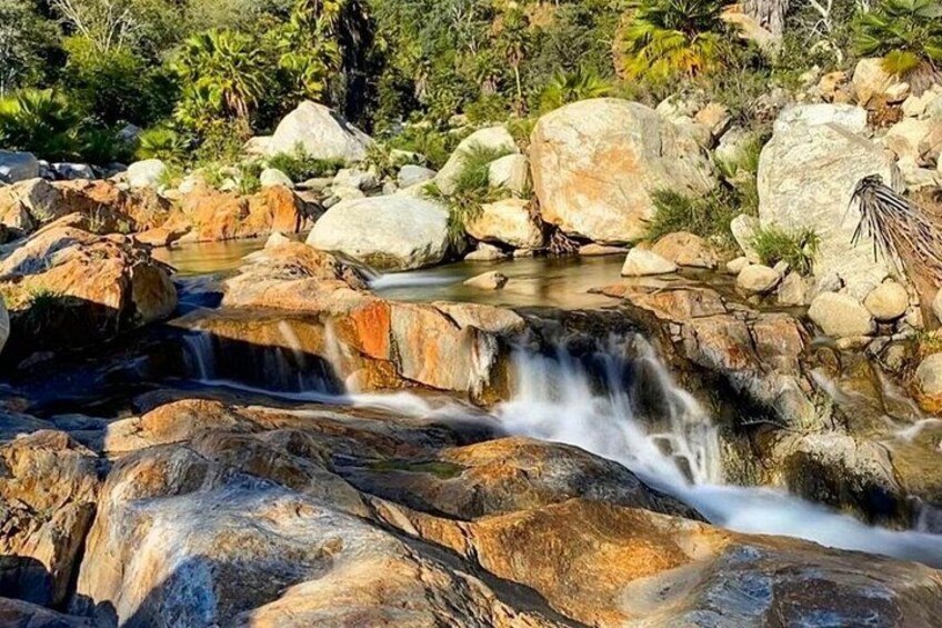 Una cascada que se precipita sobre rocas en un entorno natural con vegetación circundante. 1