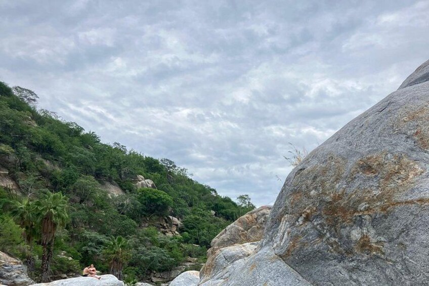 Un paisaje rocoso con grandes rocas y vegetación verde tupida. 2
