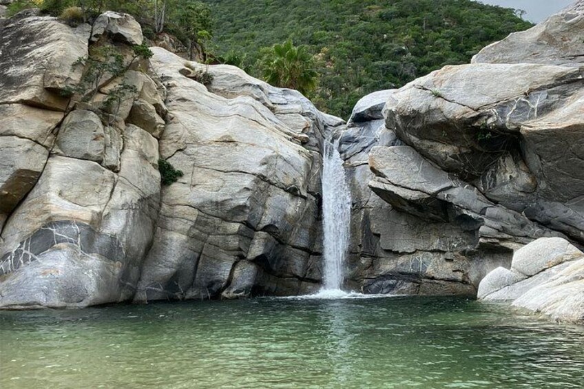 Une cascade se précipite le long d’une falaise rocheuse et se déverse dans un bassin d’eau limpide. 1