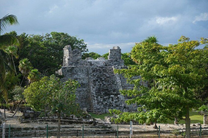 A stone ruin with a staircase, surrounded by lush greenery and trees. 4