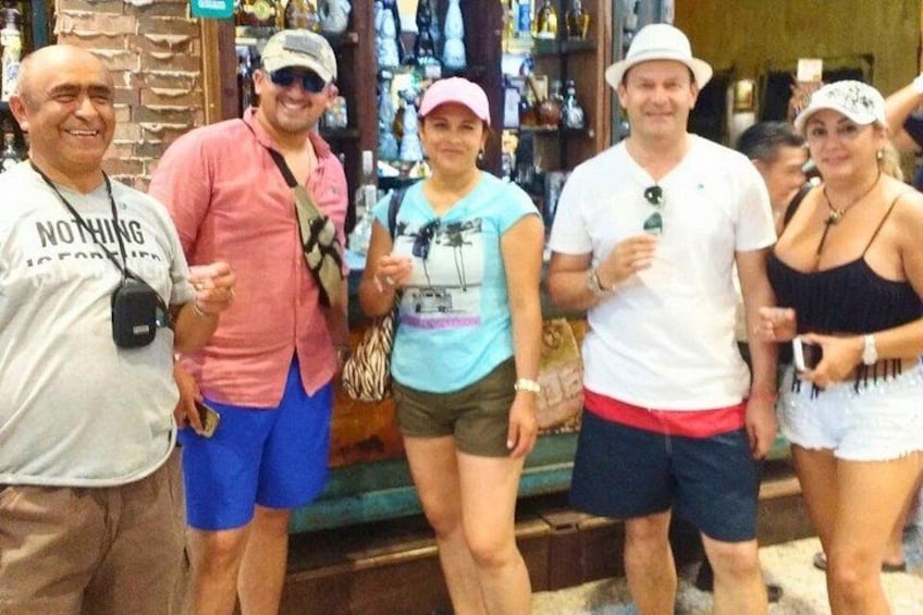 Un grupo de personas de pie en una tienda, con estantes llenos de bebidas embotelladas al fondo. 2