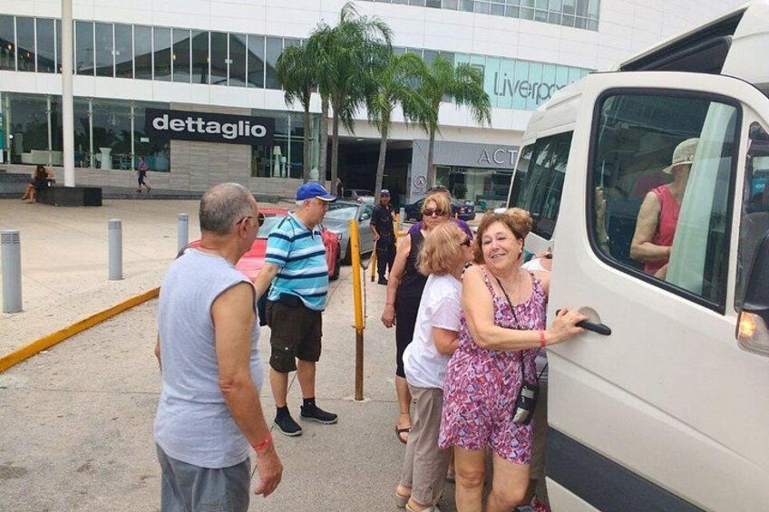 A group of people interacting with a white van in front of a building with a 'dettaglio' sign. 2