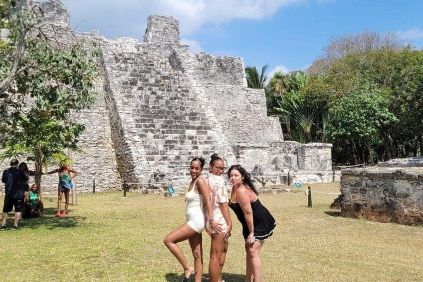A group of people posing in front of ancient ruins with a pyramid structure in the background. 2