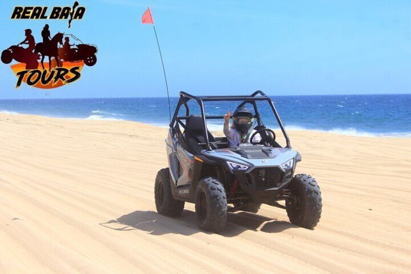 A dune buggy on a sandy beach with the ocean in the background. 5