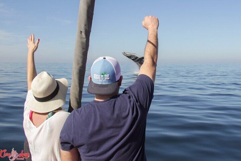 Two people on a boat, one raising their hand and the other pointing towards the water. 5
