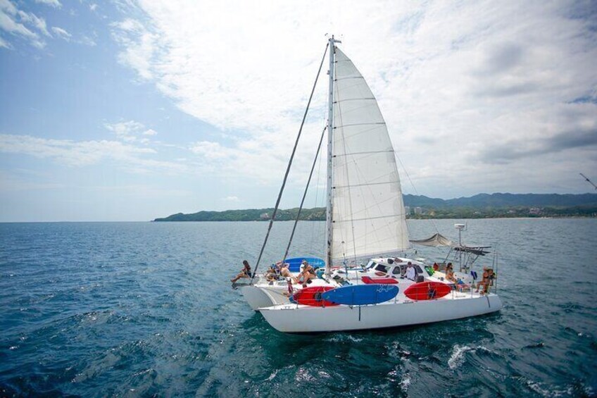 A sailboat with people on board, sailing on a body of water with a distant shoreline. 1