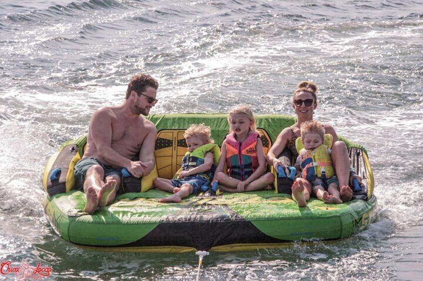A family on a green inflatable raft in the water. 3