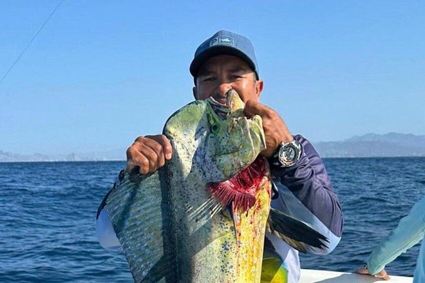 A person holding a fish on a boat with a clear blue sky and water in the background. 4