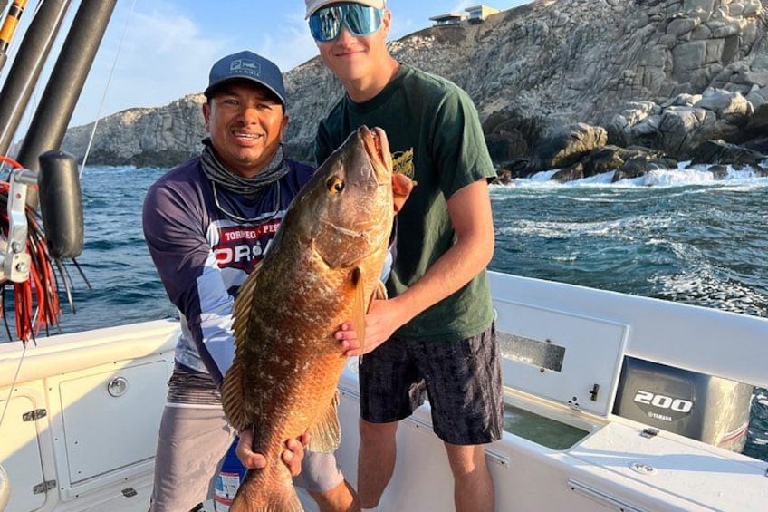 Two people on a boat holding a large fish. 5