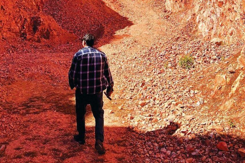 Eine Person geht auf einem felsigen Pfad durch eine rote Wüstenlandschaft. 1