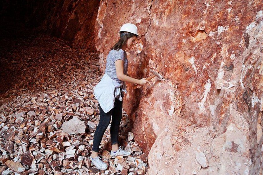 A person examining a rocky surface in a cave. 1