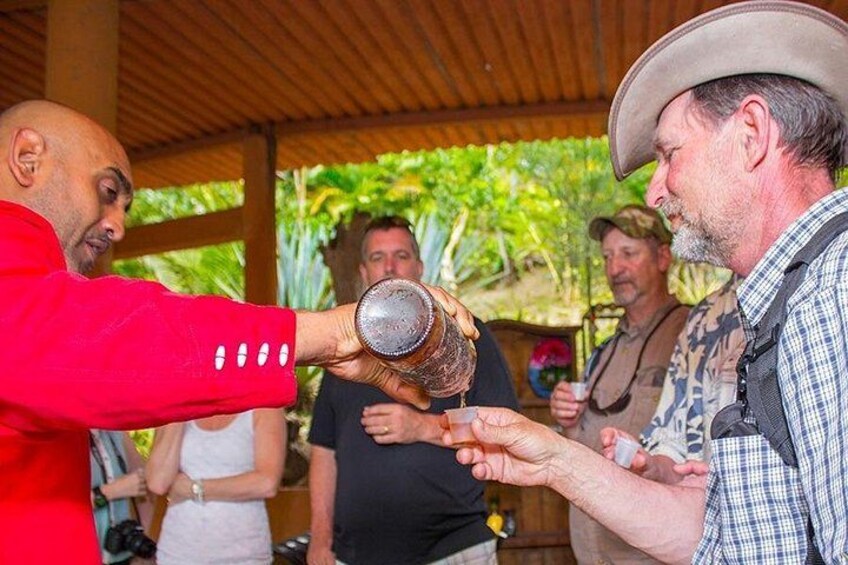 A man pouring a drink into a glass held by another man. 1