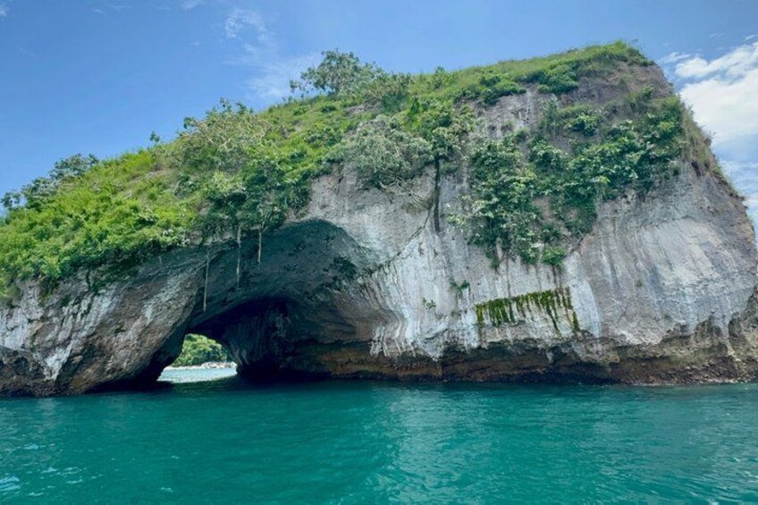 Une grande formation rocheuse surmontée d’une arche naturelle, au-dessus d’une eau turquoise. 3