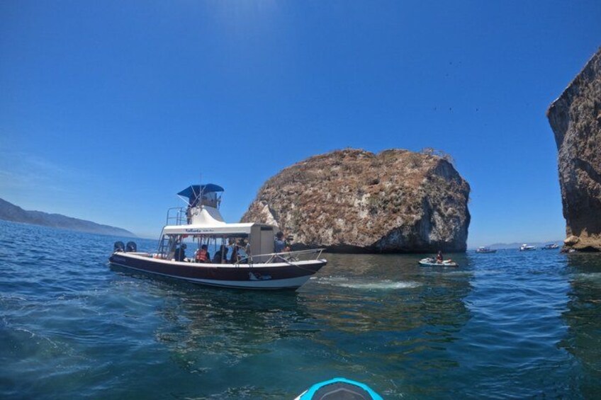 Un bateau transportant des passagers, une grande formation rocheuse et une eau calme. 5