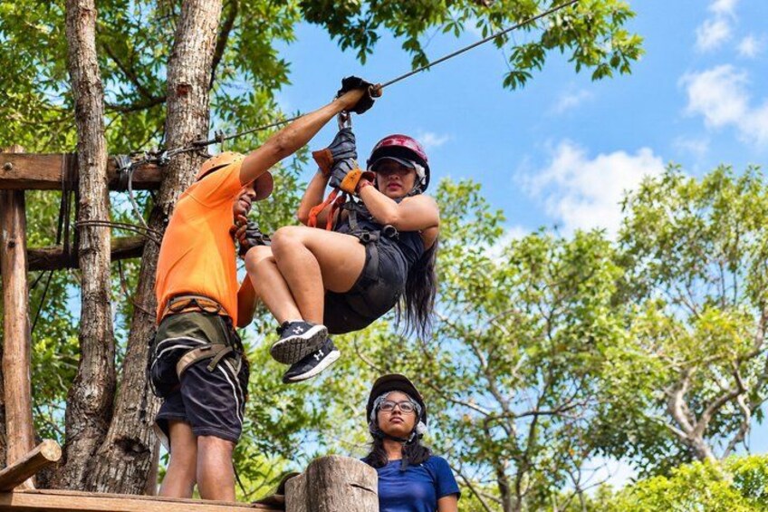 A person zip-lining, another assisting, and a third observing. 2