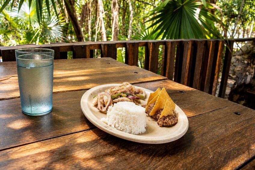 A wooden table with a plate of food and a glass of water. 3
