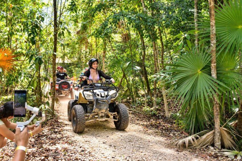 An off-road vehicle on a dirt path surrounded by dense tropical foliage. 4