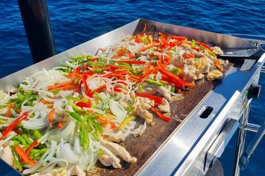 A grill with sliced vegetables and meat on a boat. 3